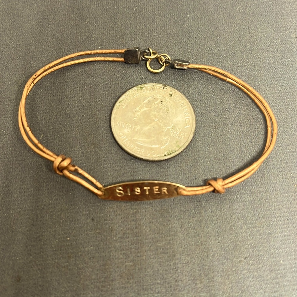 Copper bracelet stamped “sister”.